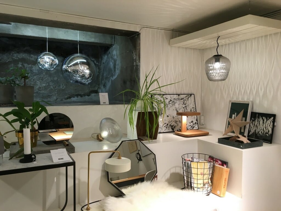 Ett modernt svenskt designshowroom med glaslampor, minimalistiska hyllor och växter som visar upp ren och elegant design.