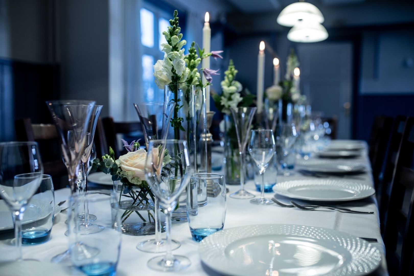 Festligt dukat långbord med blommor, glas och tända ljus